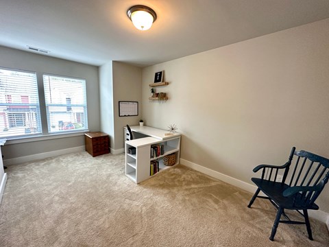 an empty living room with a desk and chair and a window