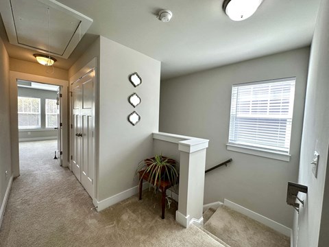 a hallway with a staircase and a window and a wall with a mirror