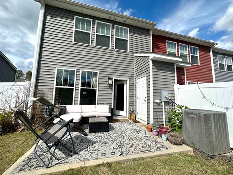 a patio with a couch and chairs in front of a house