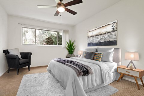 A bedroom with a large bed, a chair, and a ceiling fan.