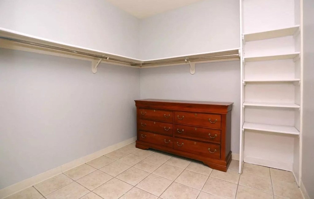 a walk in closet with a dresser and shelves