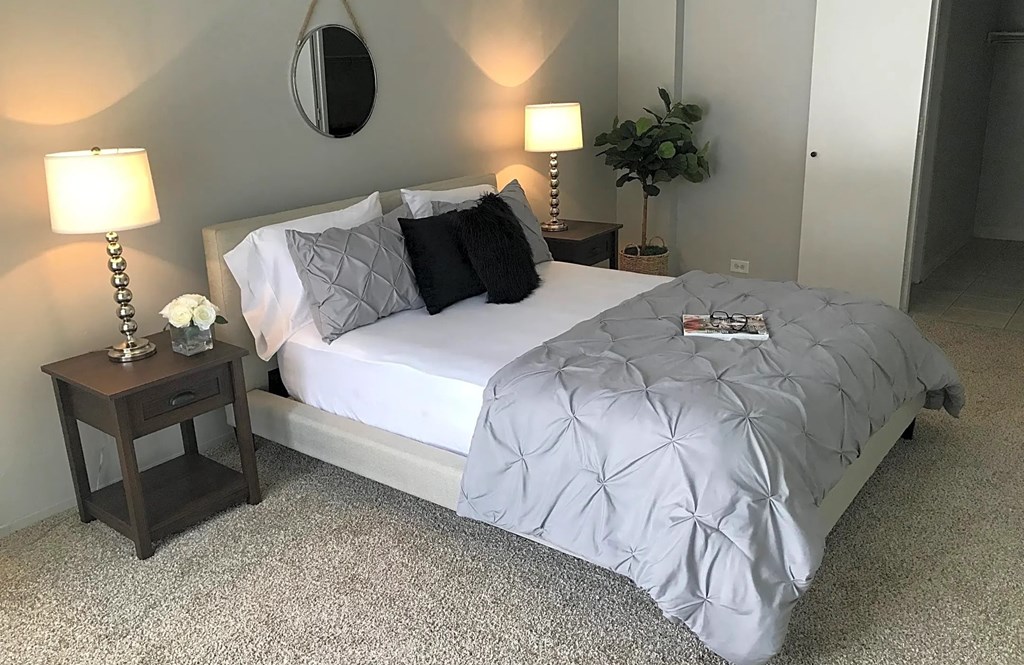 a bedroom with a bed and two lamps and a mirror