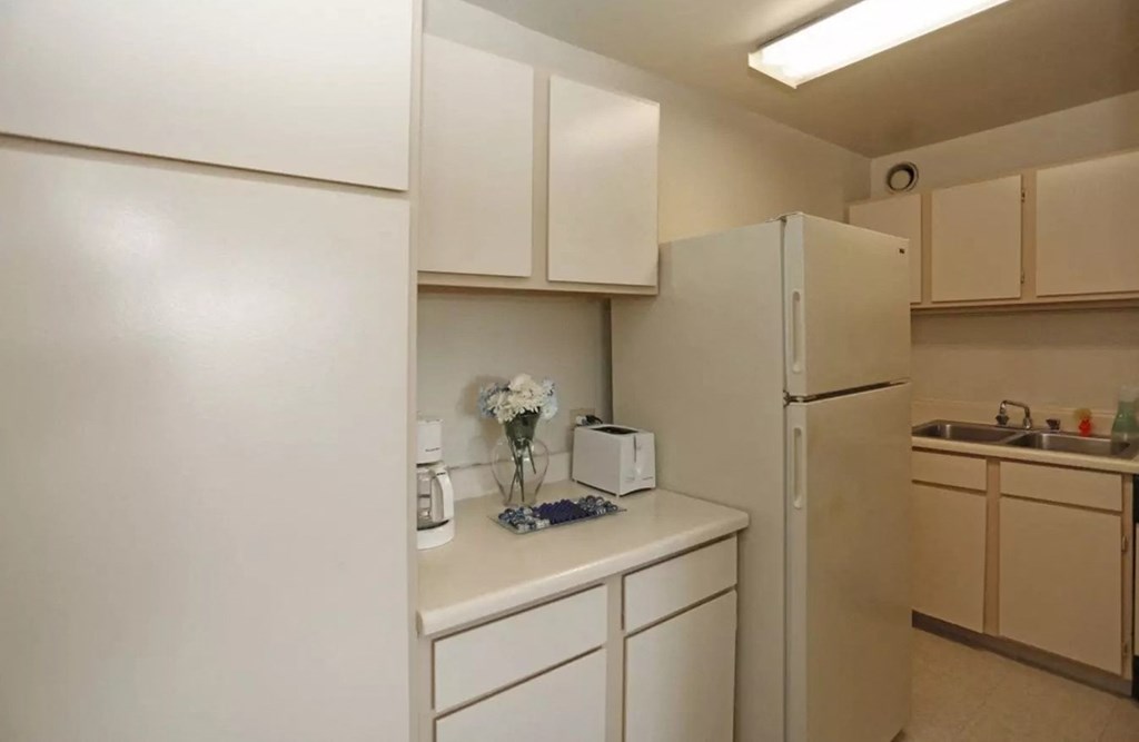 a kitchen with white cabinets and a refrigerator and a sink