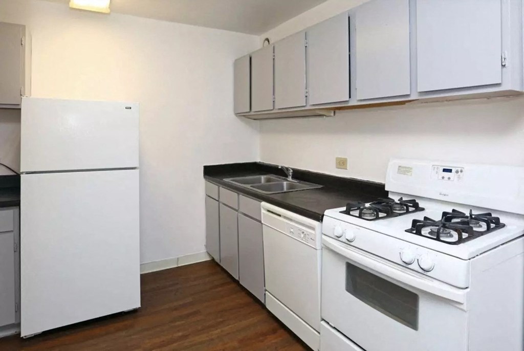 an empty kitchen with white appliances and white cabinets