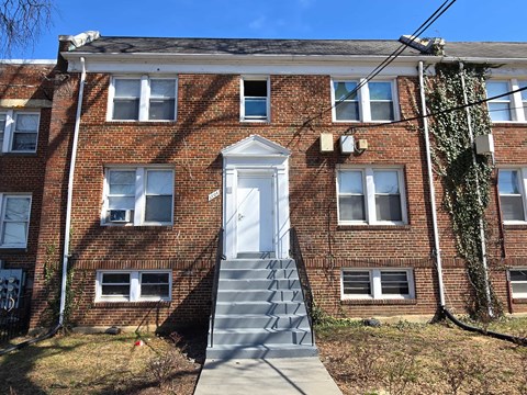 A red brick building with a white door and stairs leading up to it.