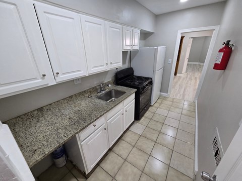 A kitchen with white cabinets and a granite countertop.