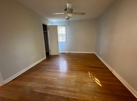 an empty living room with wooden floors and a ceiling fan