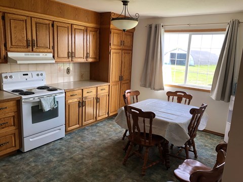 A kitchen with a stove, table and chairs.