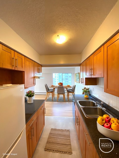 A kitchen with a refrigerator, sink, and dining table.
