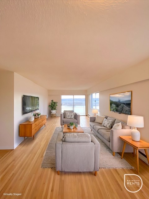 A living room with a grey couch and a wooden floor.