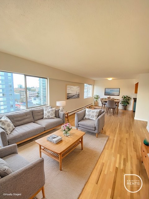 A living room with a grey couch, a wooden coffee table, and a painting on the wall.