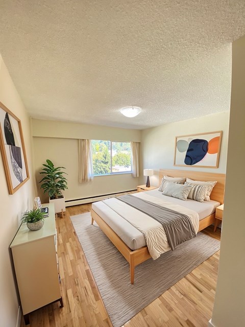 A bedroom with a large bed and a window with a view of trees.