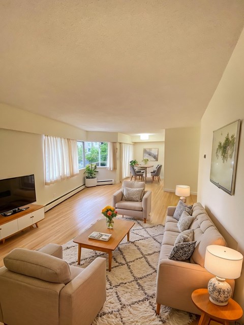 A living room with a couch, chairs, and a television.
