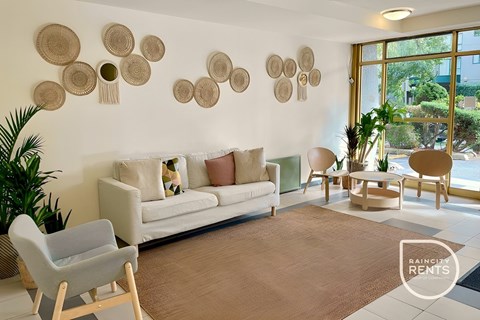 A living room with a white couch, a chair, and a table with a plant on it.