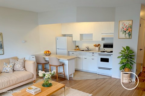 A well-lit kitchen with white cabinets and a dining table with chairs.