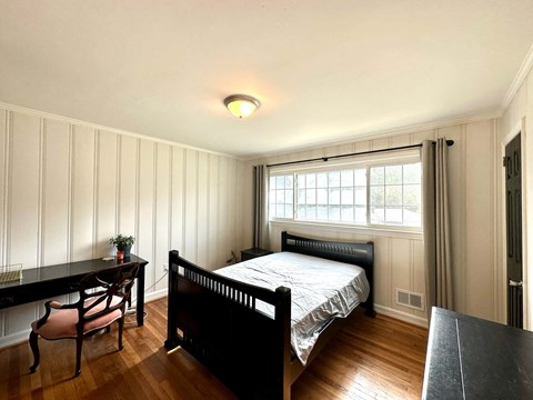a bedroom with a bed and a desk and a window