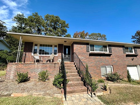 the front of a brick house with stairs and a porch