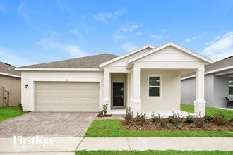 a white house with a garage door and a lawn