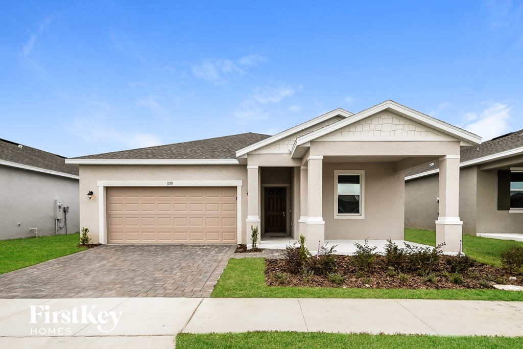a white house with a garage door and a lawn