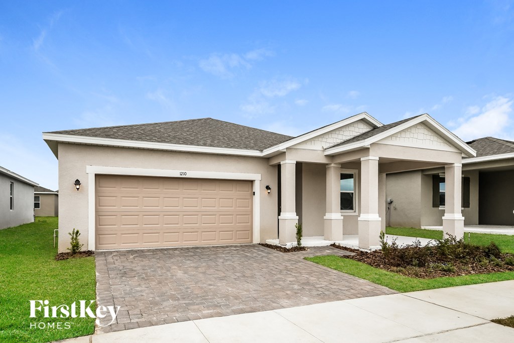 a beige house with a garage door and a lawn
