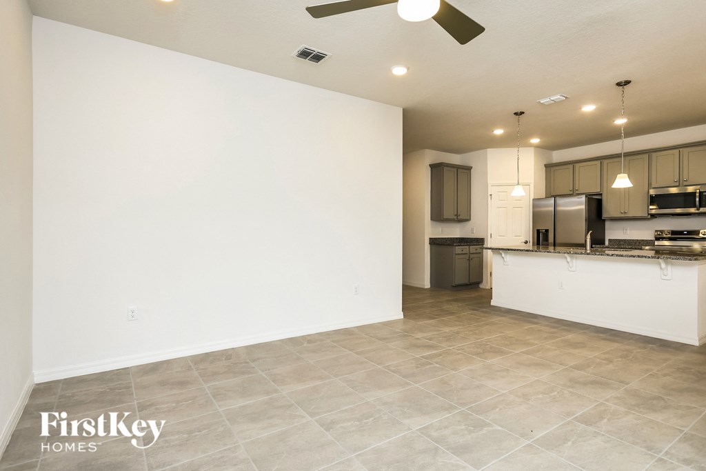 a kitchen and living room with white walls and tile flooring