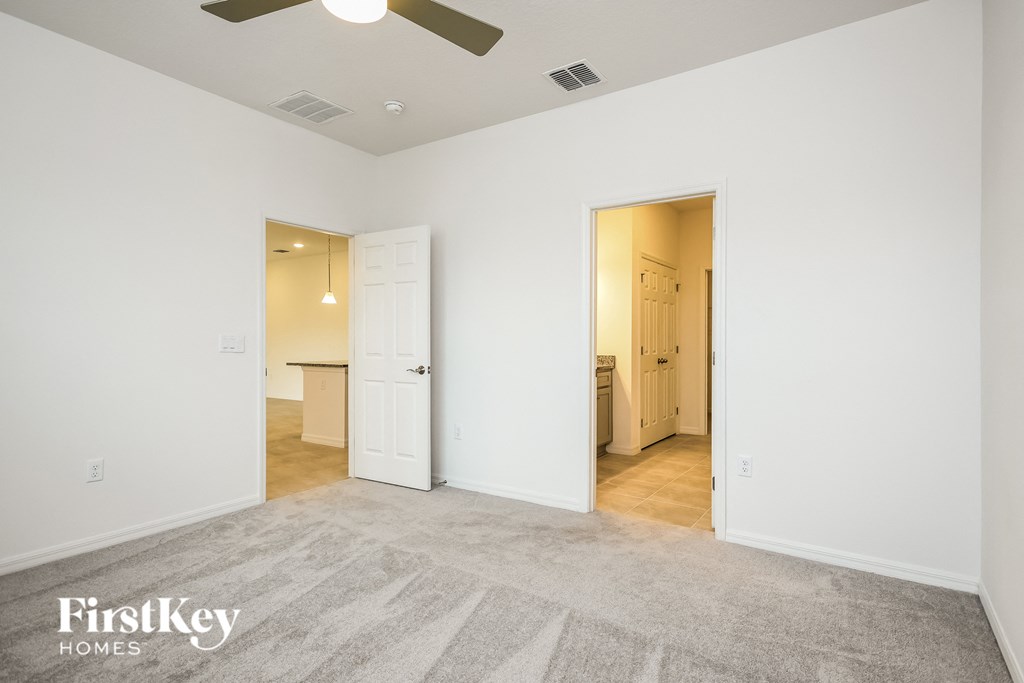 an empty living room with a ceiling fan and a door to a bathroom