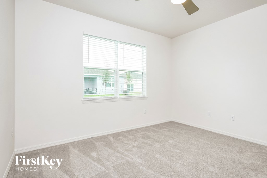 a bedroom with white walls and a window
