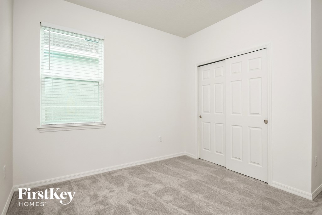 a bedroom with white walls and carpet and a white door