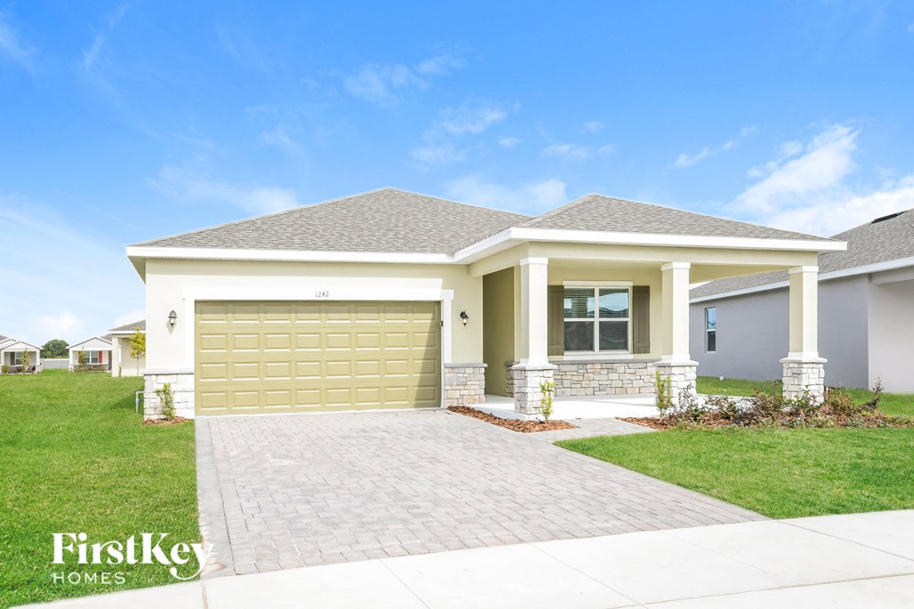A house with a garage door and a driveway in front.