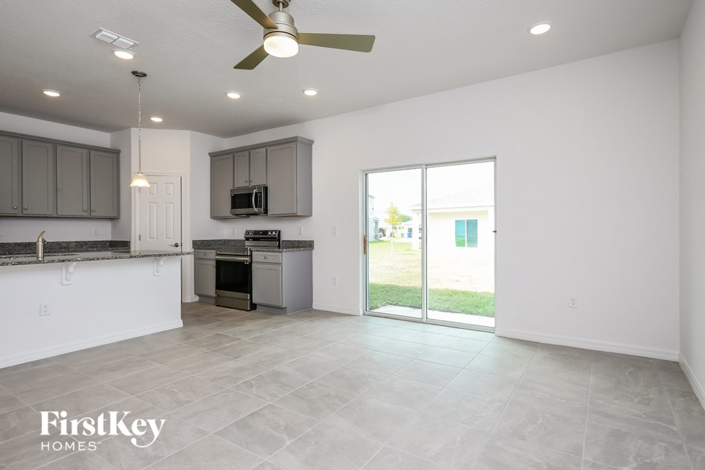A spacious kitchen and living room with a sliding glass door leading to a backyard.