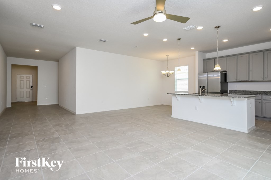A spacious kitchen and living room with a white ceiling fan and lighting.