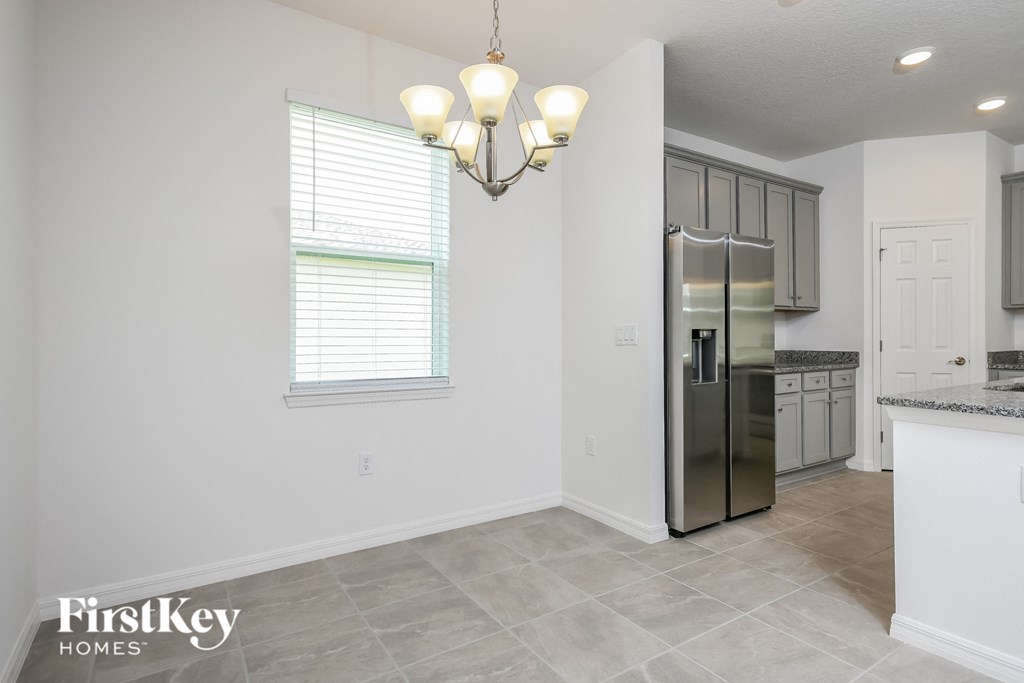 A kitchen with a stainless steel refrigerator and a chandelier hanging from the ceiling.