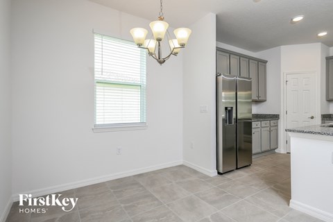 A kitchen with a stainless steel refrigerator and a chandelier hanging from the ceiling.