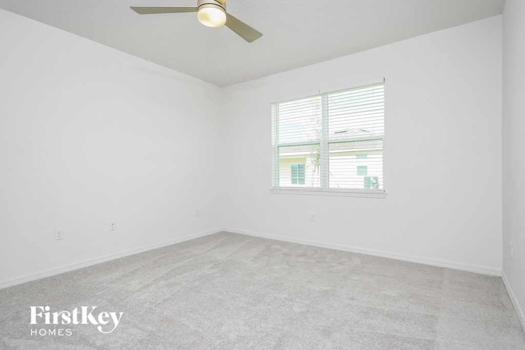 A room with a ceiling fan and a window with blinds.