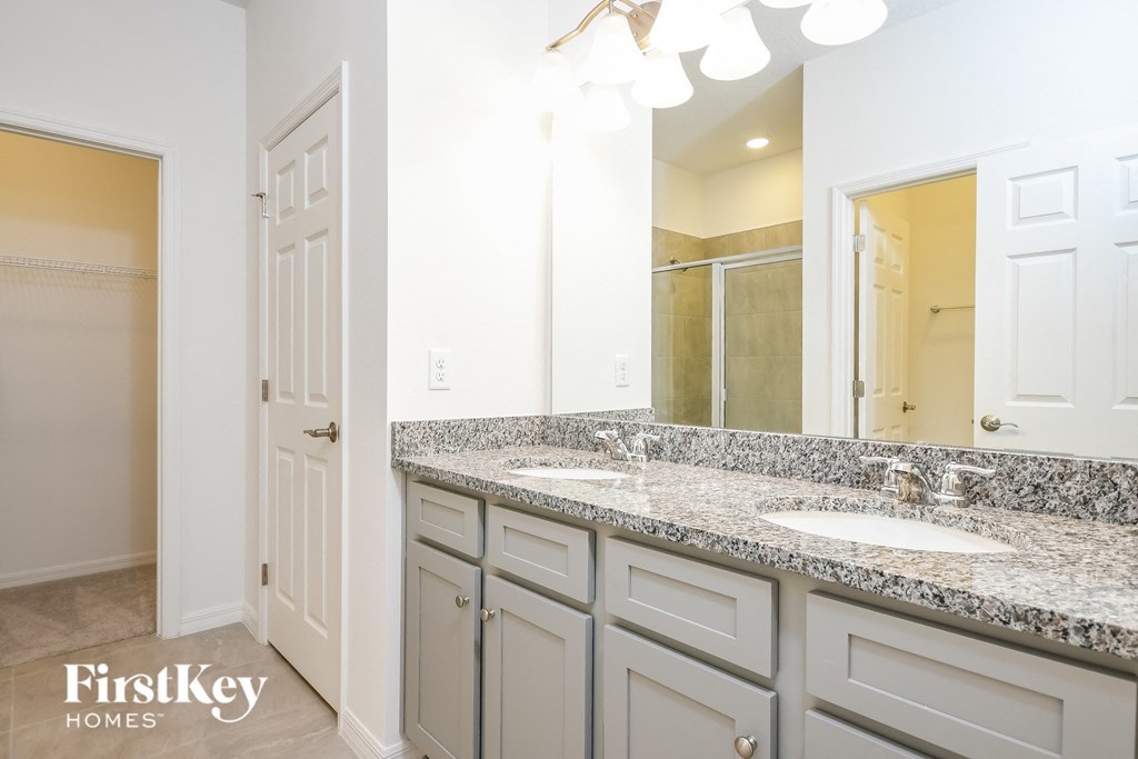 A bathroom with a granite countertop and a large mirror.