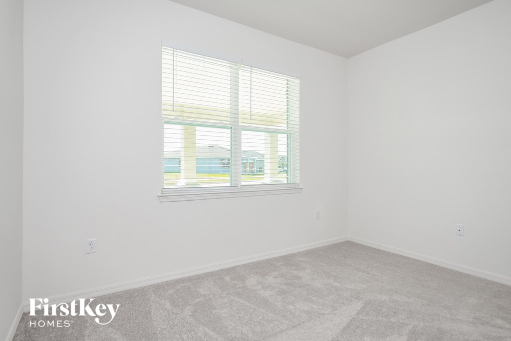 A room with a window showing a view of a building and trees outside.
