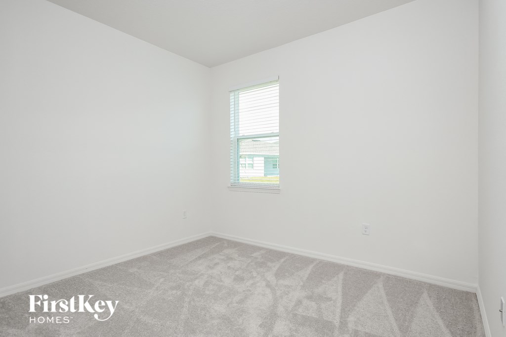 A room with a carpeted floor and a window with blinds.