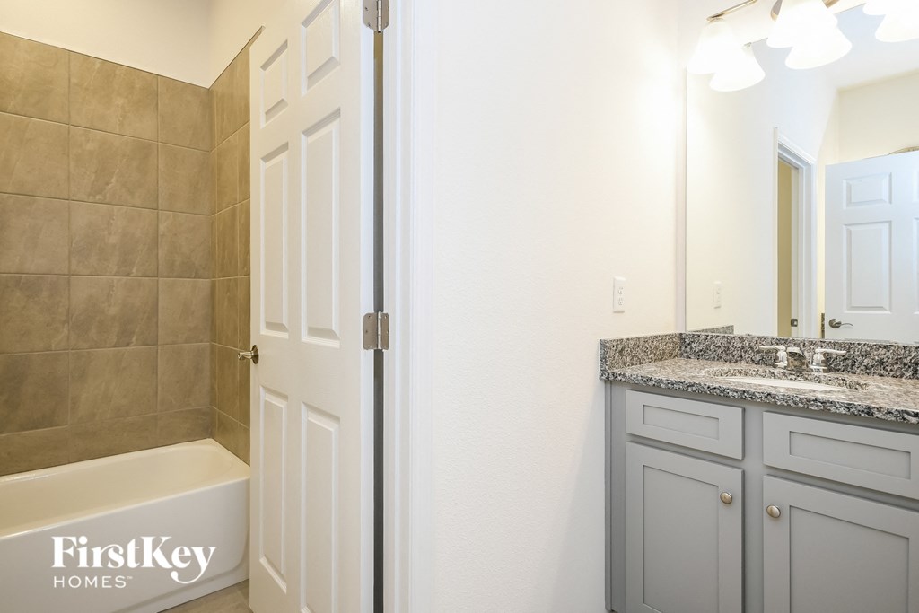 A bathroom with a tub, sink, and mirror.