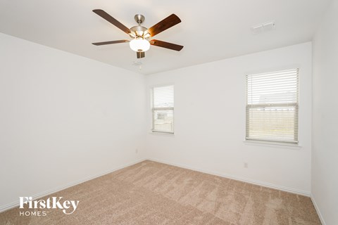 a living room with a ceiling fan and a carpet