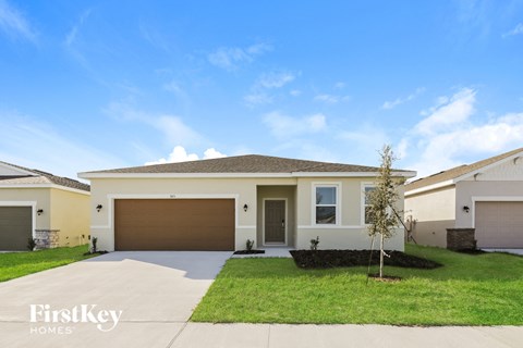 a beige house with a garage door and a lawn
