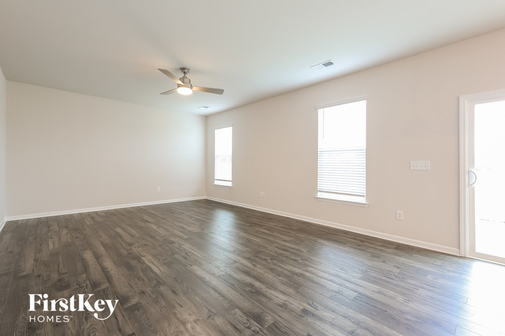the spacious living room with wood floors and a ceiling fan