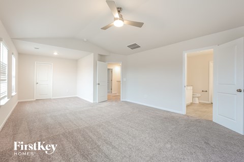 a spacious living room with a ceiling fan and a carpet