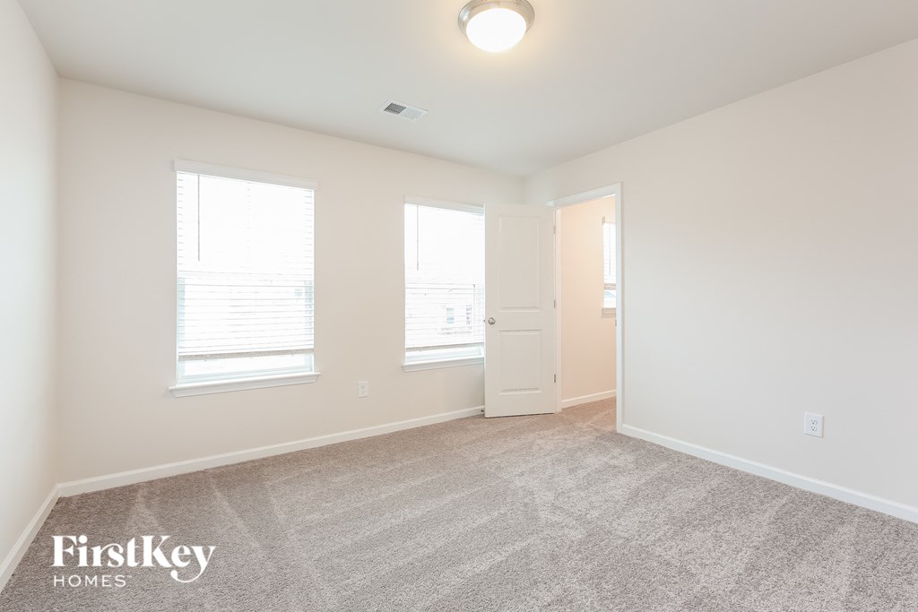 a spacious living room with two windows and a door