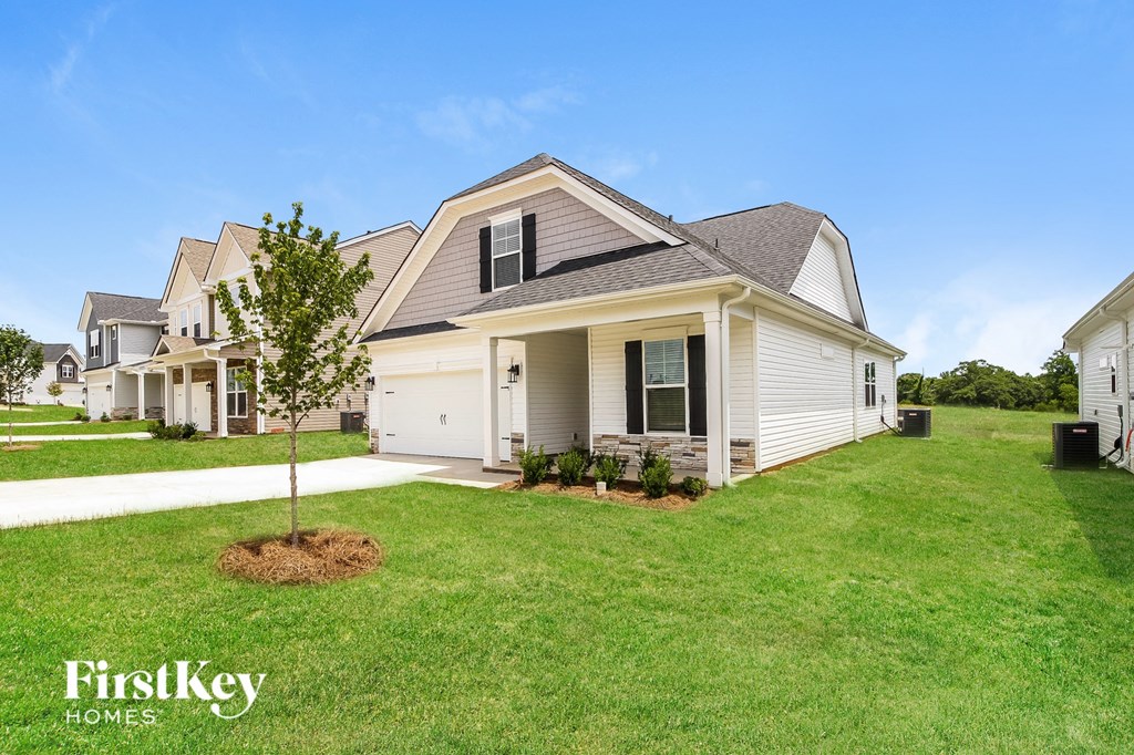 a row of white houses with a lawn and a tree