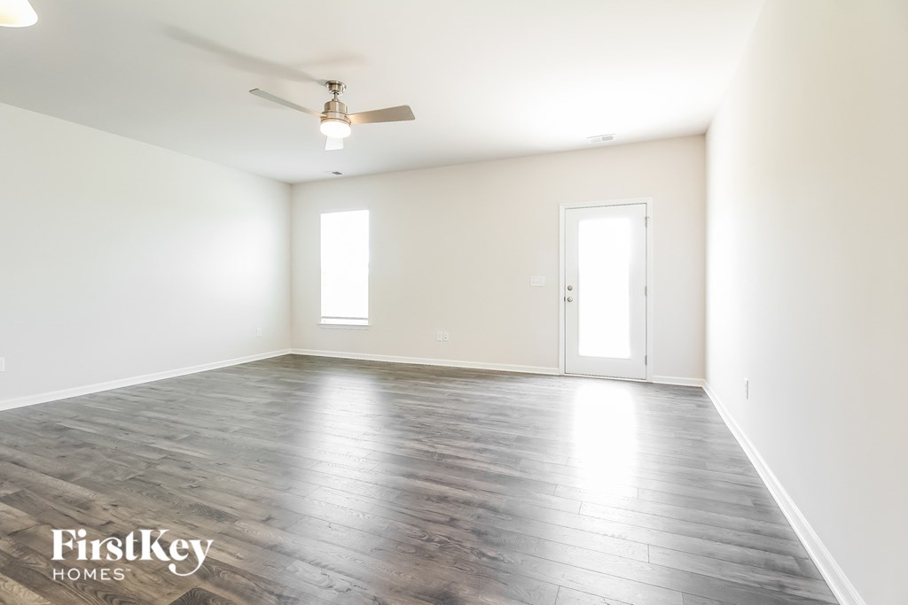 an empty living room with white walls and a ceiling fan