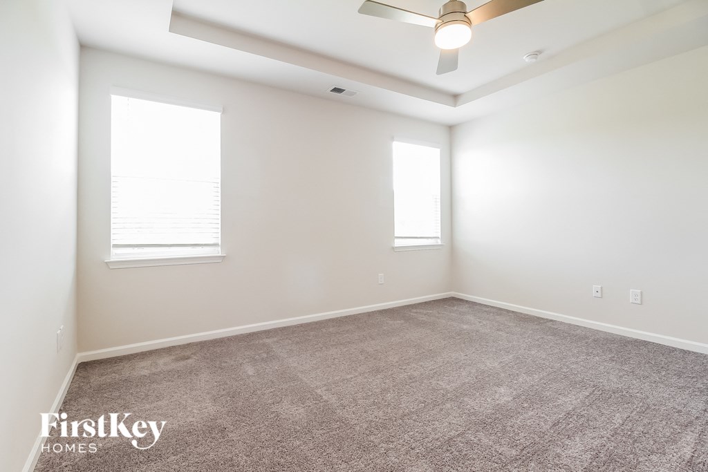 an empty room with two windows and a ceiling fan