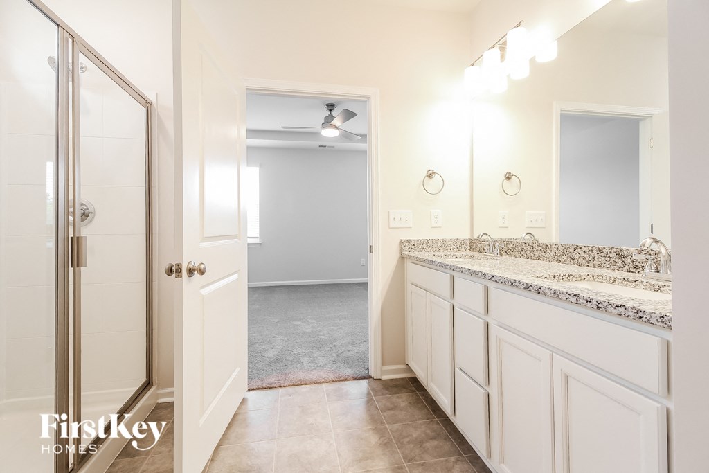 a bathroom with white cabinets and a large mirror and a shower