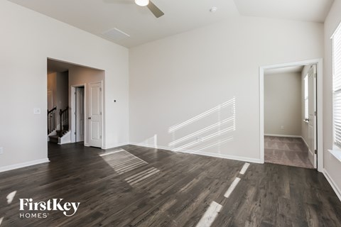 A spacious room with wooden flooring and a staircase leading to another room.