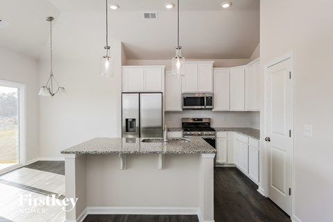 A kitchen with a granite countertop and a microwave on top.