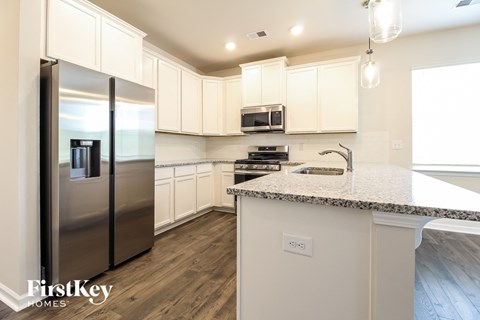 a kitchen with white cabinets and a counter top and stainless steel refrigerator